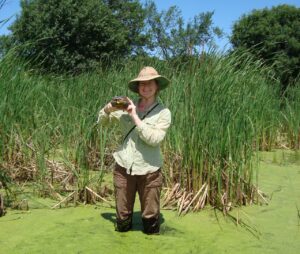 Tanya Matlaga in a wetland holding a turtle