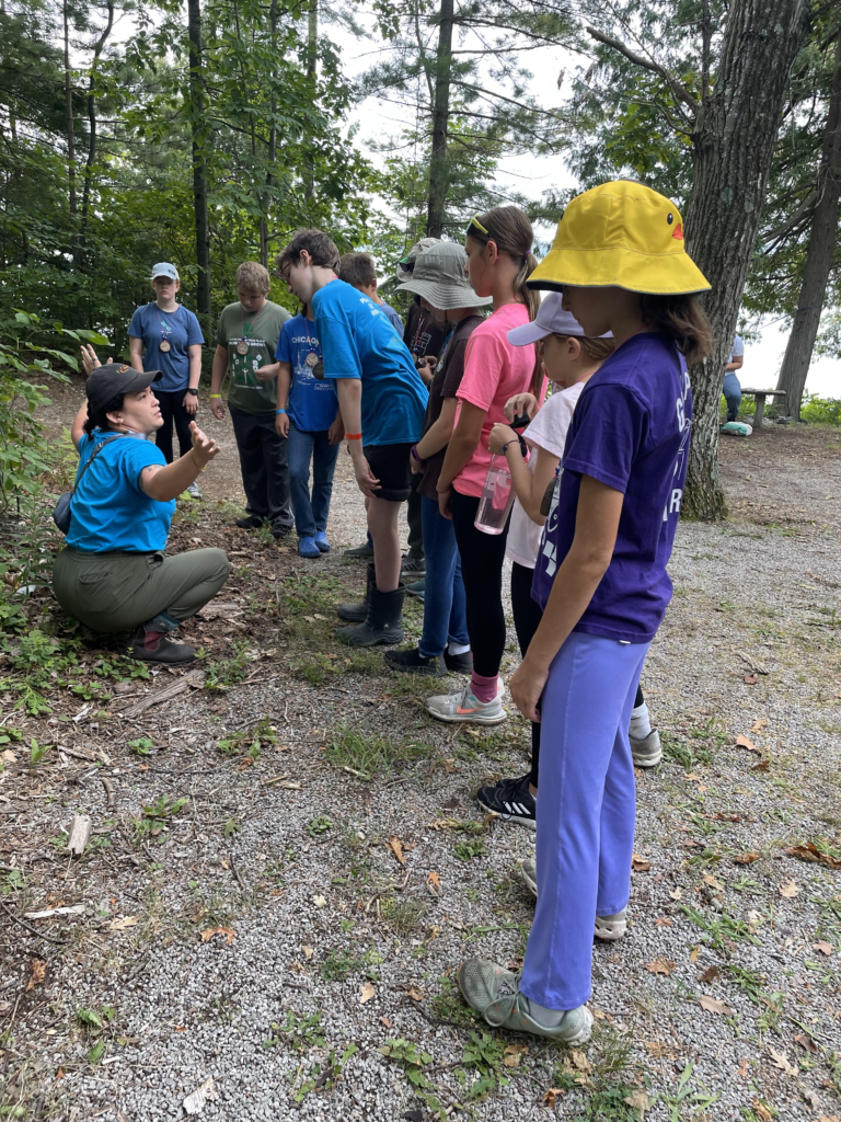 Sophia Loureiro, a mentee in the 2024-2025 SPARCnet RaMP Program, leads a group of budding conservations and explains how to safely and responsibly look for reptiles and amphibians in the forest at the 4-H Great Lakes and Natural Resources Camp.