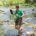 Bethany Ozolins doing field work in a stream.